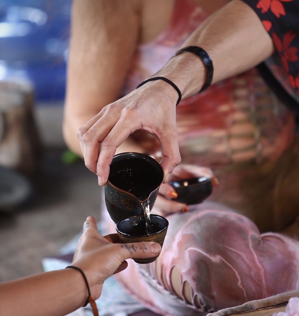 A small dark tea cup being passed from Jake's hand into a guest's hand
